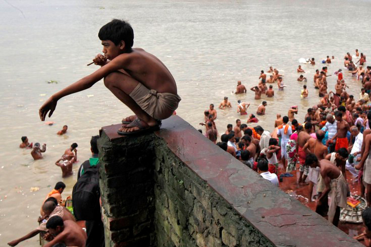 Ένα νεαρό αγόρι  παρακολουθεί από ψηλά τις  βουτιές των συμπατριωτών του στις όχθες του Γάγγη ποταμού, γιορτάζοντας την ιερή ημέρα της "Mahalaya", στην Καλκούτα της Ινδίας 
